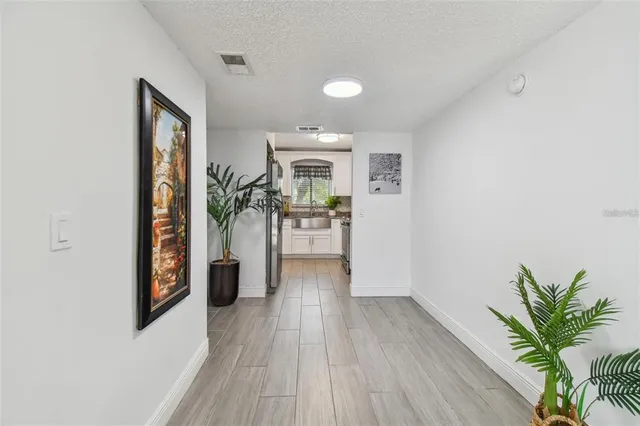 a view of a hallway with wooden floor and a living room
