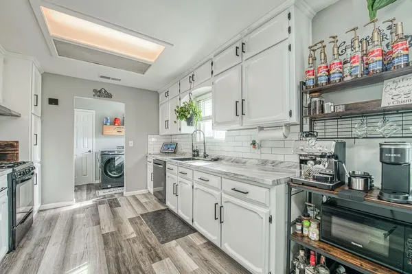a large kitchen with stainless steel appliances granite countertop a lot of counter space and wooden floors