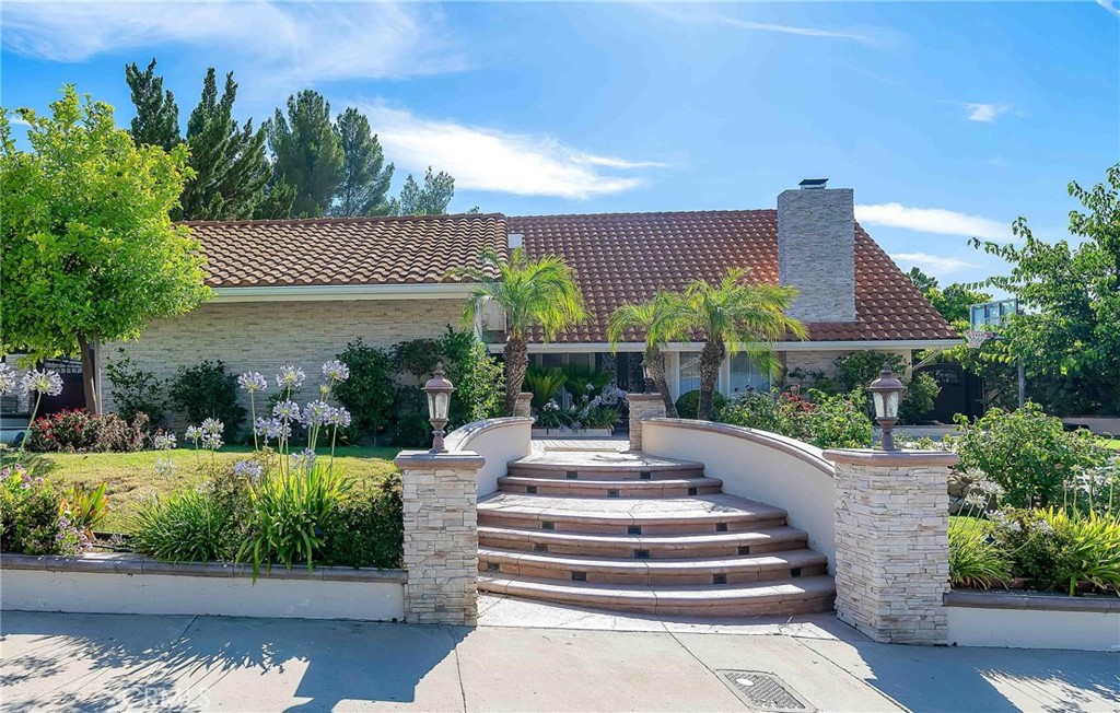 a front view of a house with fountain and plants