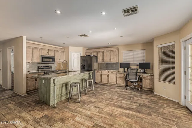 a kitchen with stainless steel appliances kitchen island granite countertop a stove a sink a refrigerator and a refrigerator