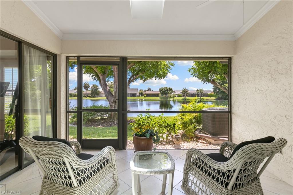 Sunroom featuring a textured wall, crown molding, tile patterned floors, and a water view
