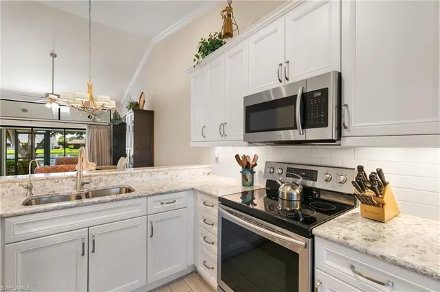 a kitchen with stainless steel appliances granite countertop a sink a stove a microwave and wooden cabinets