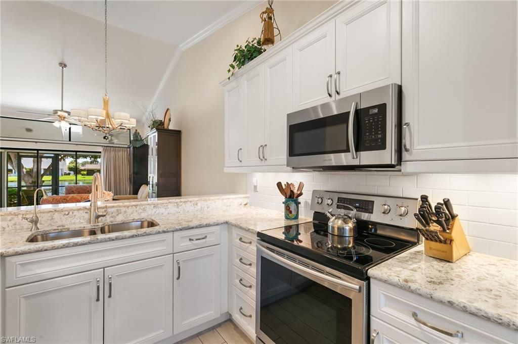 3346 Erick Lake Drive, Unit 2001 Naples, FL 34109 - Photo 11 of 43 a kitchen with stainless steel appliances granite countertop a sink a stove a microwave and wooden cabinets