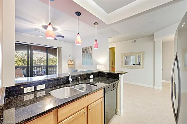 a kitchen with granite countertop a sink a counter top space and living room view
