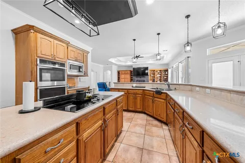 a open kitchen with stainless steel appliances granite countertop a stove a refrigerator a oven a sink with a dining table and chairs with wooden floor