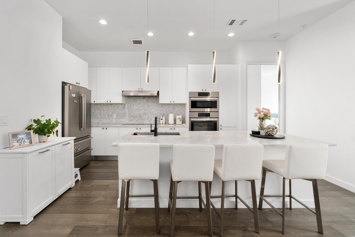 800 Embassy Drive, Unit 609 Austin, TX 78702 - Photo 4 of 33 a kitchen with stainless steel appliances kitchen island granite countertop a table chairs sink and cabinets