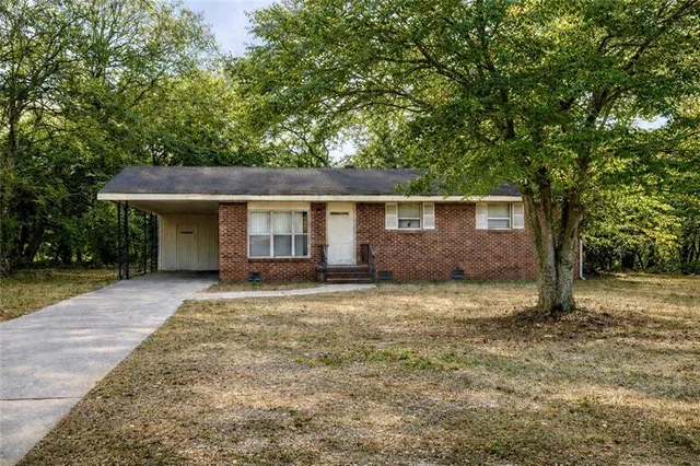 a view of a house with a yard and large tree