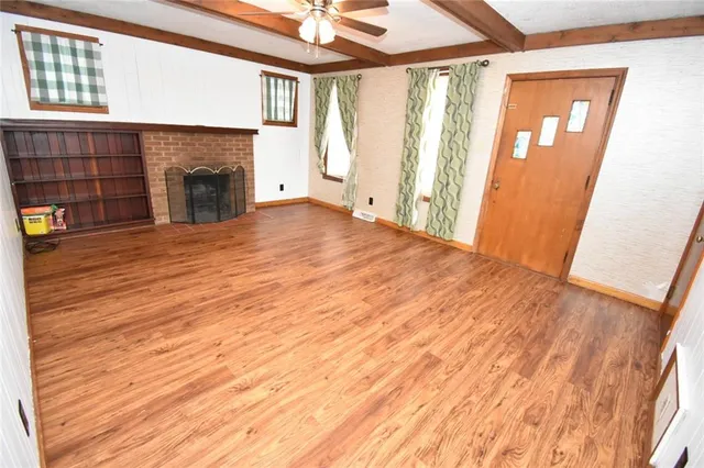 a view of empty room with wooden floor and fireplace