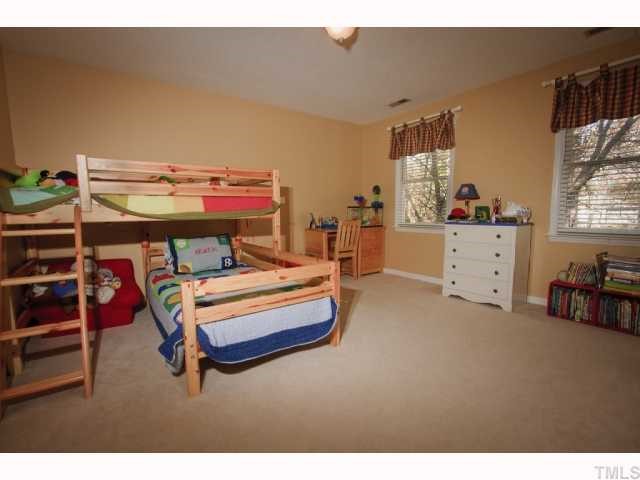 8305 Morgans Way Raleigh, NC 27613 - Photo 7 of 12 a bedroom with a bed and a chandelier