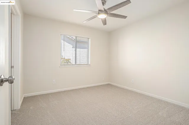 an empty room with a window and ceiling fan