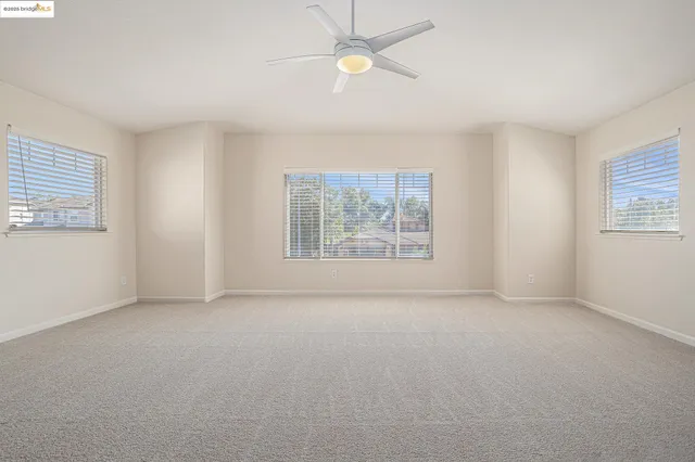 an empty room with windows and fan