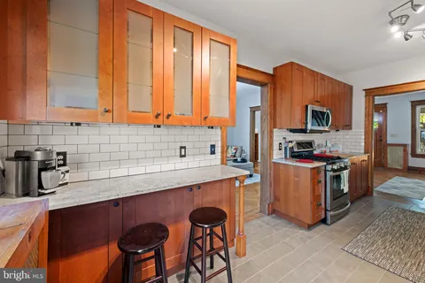 a kitchen with stainless steel appliances a sink a stove a refrigerator cabinets and a window