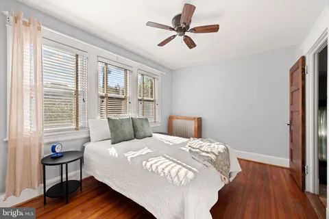 a bedroom with a bed a dresser and a wooden floor