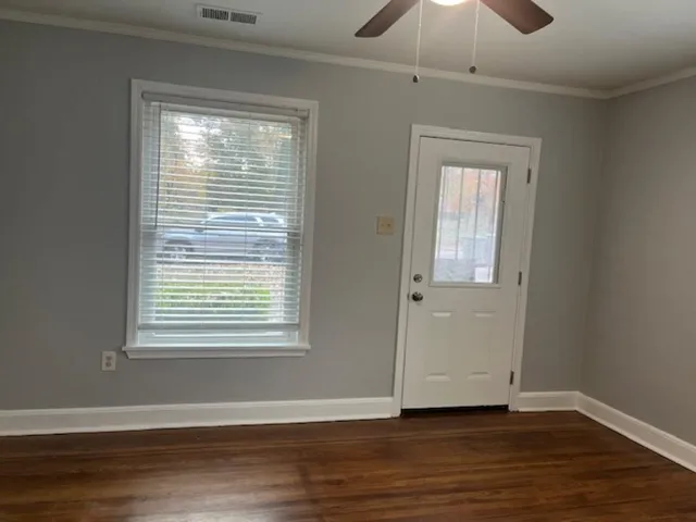 a view of an empty room with wooden floor and a window