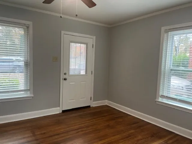 a view of an empty room with wooden floor and a window