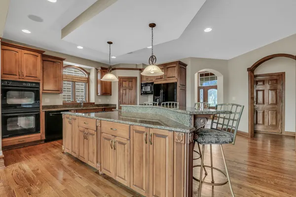 a kitchen with stainless steel appliances kitchen island granite countertop a stove and a wooden floors