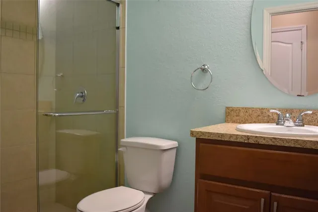a bathroom with a granite countertop toilet sink and mirror