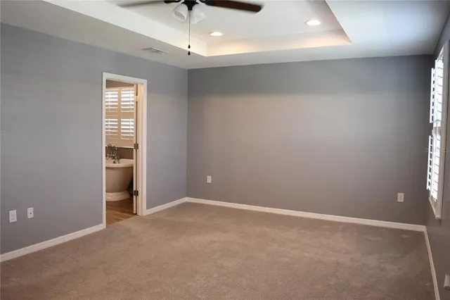an empty room with windows and chandelier fan