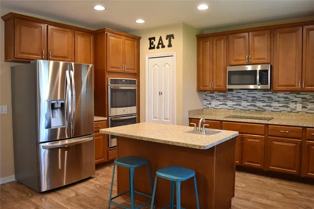 a kitchen with stainless steel appliances granite countertop a refrigerator a stove a sink and a microwave