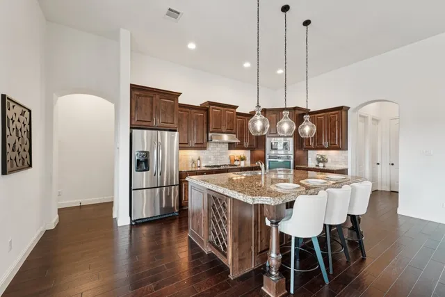 a kitchen with stainless steel appliances a dining table chairs and wooden floor