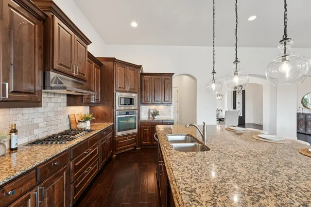 a kitchen with stainless steel appliances granite countertop a stove a sink and a refrigerator