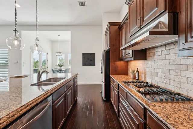 a kitchen with stainless steel appliances granite countertop a sink stove and cabinets