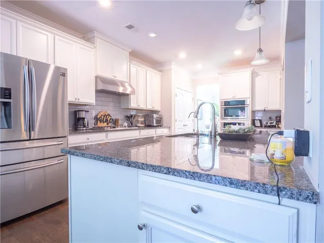 a kitchen with granite countertop a sink a counter top space appliances and cabinets