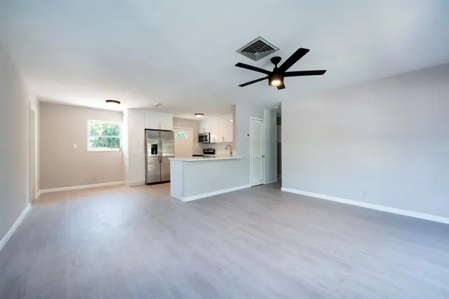 a view of a livingroom with a ceiling fan & a window