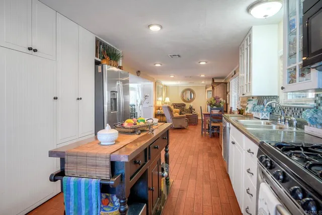 a kitchen with stainless steel appliances granite countertop a stove oven a dining table and chairs with wooden floor