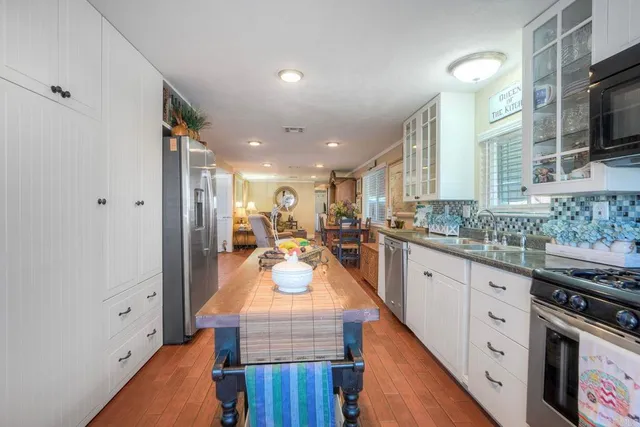 a large kitchen with kitchen island a stove a sink dishwasher and white cabinets with wooden floor