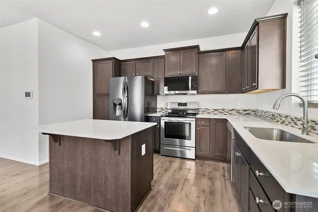 a kitchen with stainless steel appliances a sink stove refrigerator and cabinets