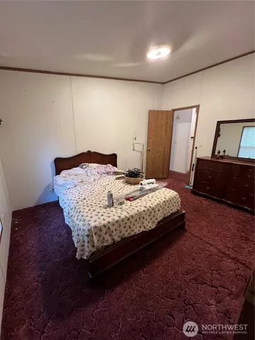 a bedroom with a bed rug and wooden floor