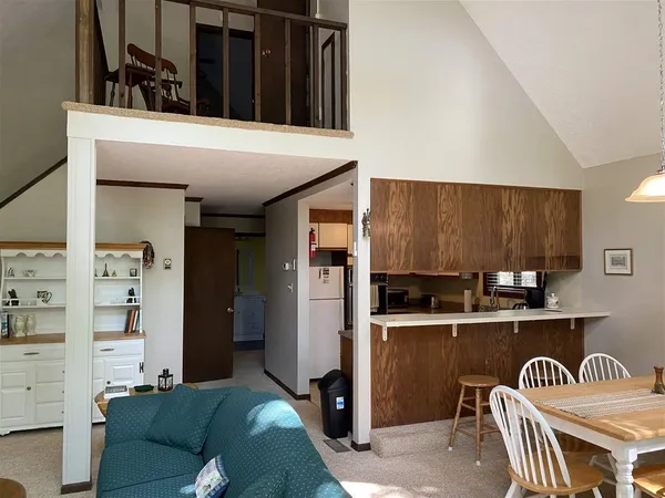 a kitchen with stainless steel appliances kitchen island granite countertop a refrigerator a sink a stove and a dining table with wooden floor