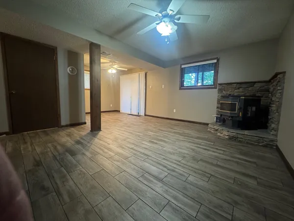 an empty room with wooden floor fireplace and windows