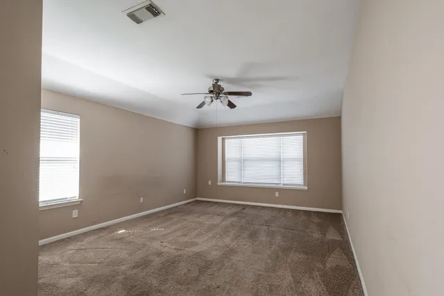 an empty room with a window and a ceiling fan