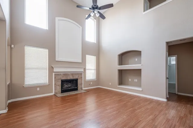 an empty room with wooden floor fireplace and windows