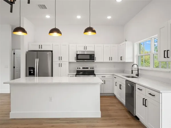 a kitchen with stainless steel appliances granite countertop a sink a stove and refrigerator