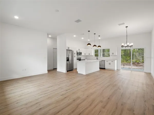 an open kitchen with a white refrigerator stove and wooden floor