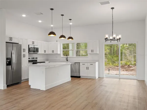 a kitchen with stainless steel appliances granite countertop a stove a refrigerator a sink dishwasher and white cabinets with wooden floor