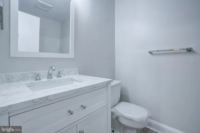 a bathroom with a granite countertop toilet sink and mirror