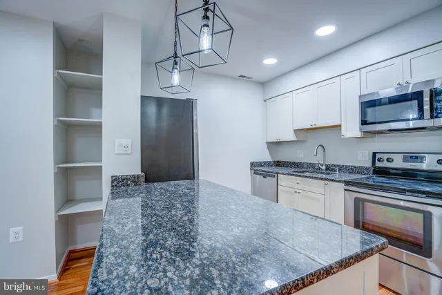 a kitchen with kitchen island granite countertop a stove sink and cabinets