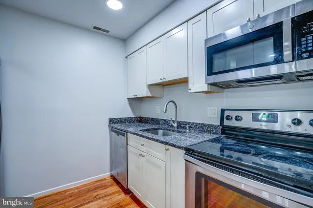 a kitchen with stainless steel appliances granite countertop a sink stove and microwave