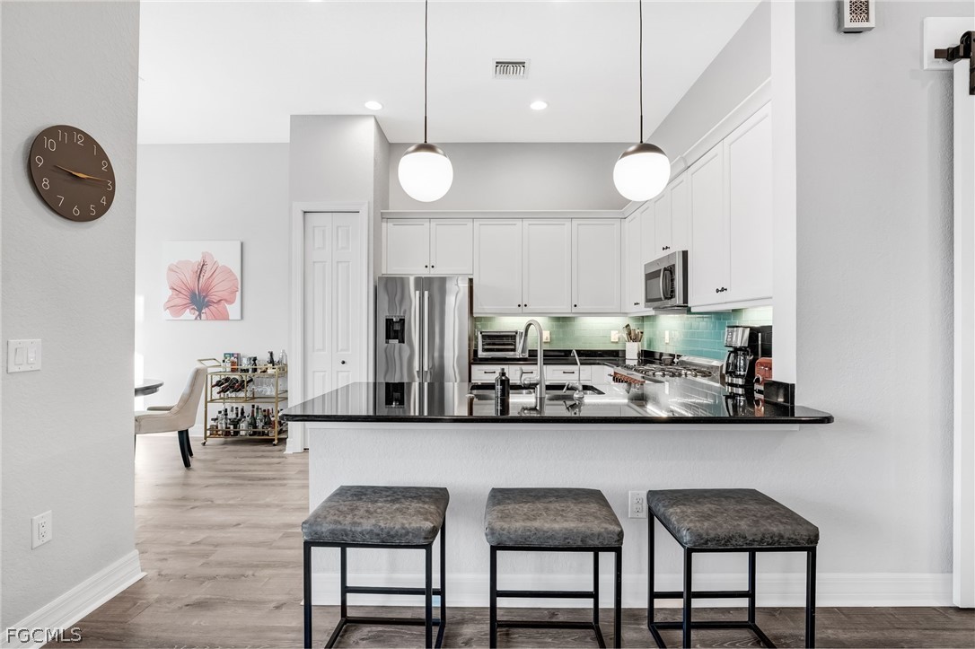 2999 Willow Ridge Court Fort Myers, FL 33905 - Photo 11 of 50 a kitchen with stainless steel appliances kitchen island granite countertop a table chairs and a refrigerator