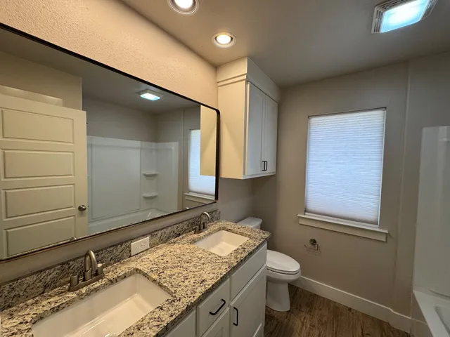 a bathroom with a granite countertop sink toilet and mirror