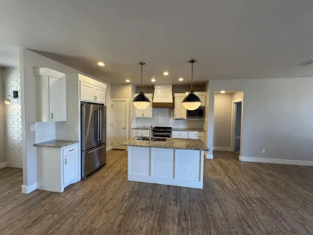 a kitchen with stainless steel appliances granite countertop a refrigerator a stove and a wooden floors