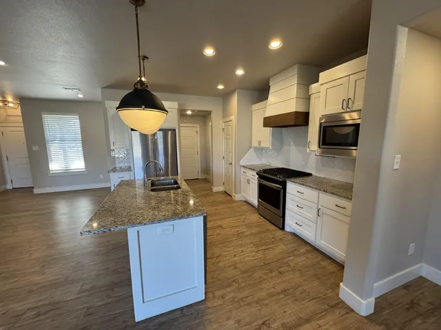 a kitchen with stainless steel appliances granite countertop a sink a stove top oven a counter space and cabinets