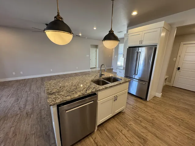 a kitchen with stainless steel appliances granite countertop a refrigerator a stove and a wooden floors