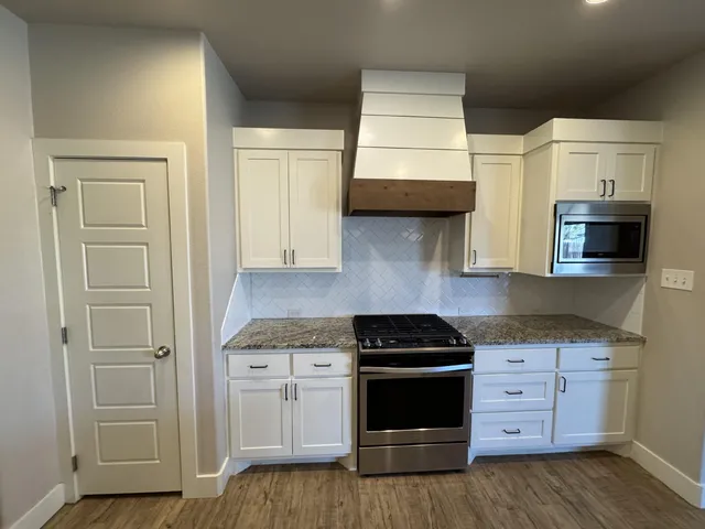 a kitchen with stainless steel appliances granite countertop white cabinets and a stove