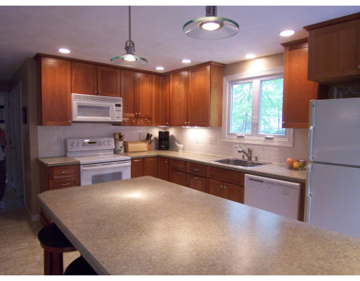 2 Parker Road Ashland, MA 01721 - Photo 7 of 29 a kitchen with stainless steel appliances kitchen island granite countertop a refrigerator a sink dishwasher a stove and white cabinets with wooden floor