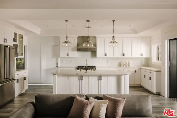 a kitchen with stainless steel appliances granite countertop a refrigerator a sink dishwasher a dining table and chairs with wooden floor